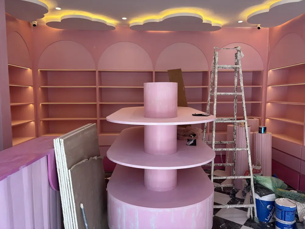 Confiserie à Guéliz, Marrakech, en fin de chantier : étagères en arche roses, présentoir circulaire, plafond en nuages lumineux