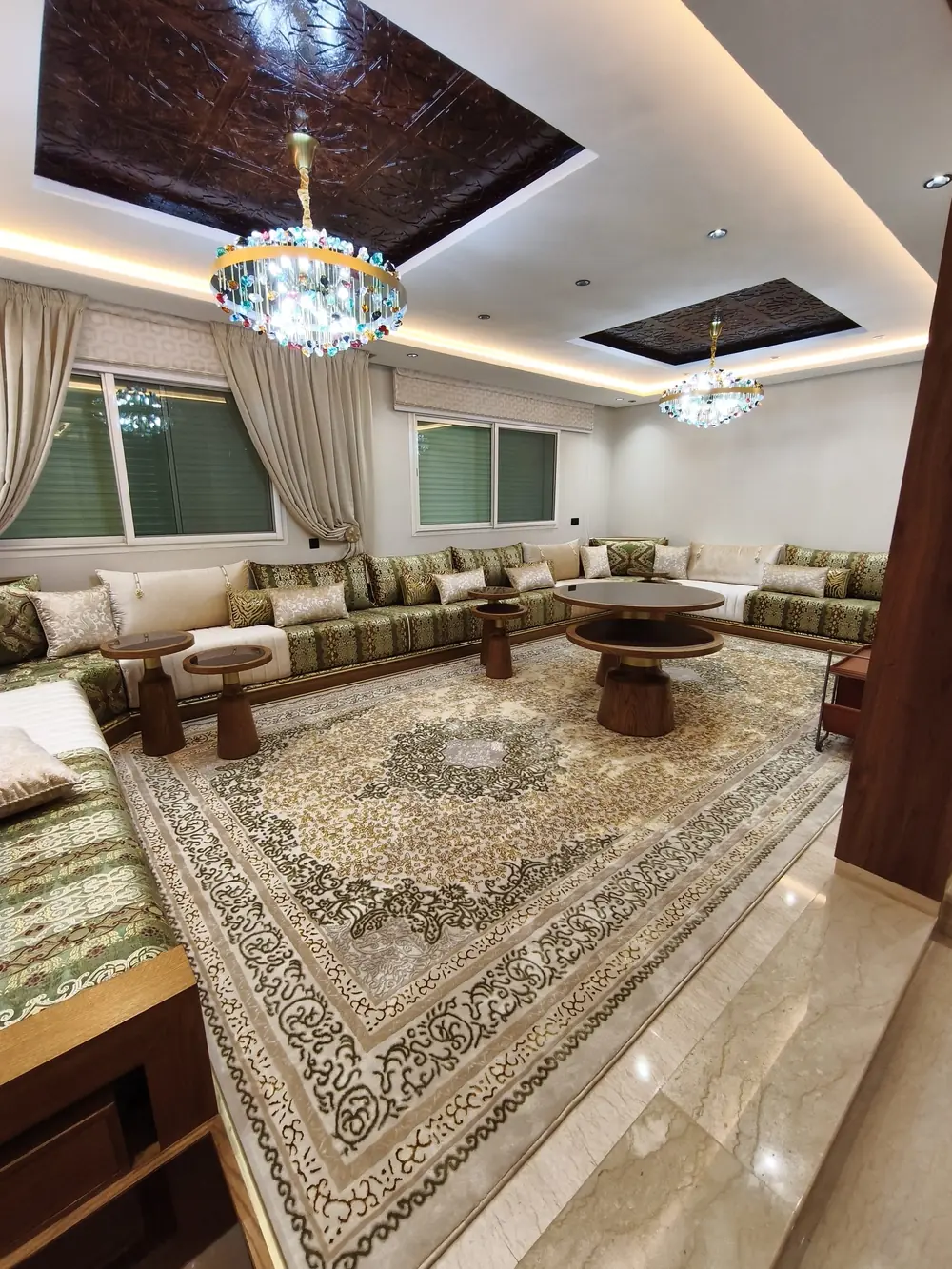 Grand salon d'une villa rénovée à Rabat : plafonds lumineux et lustre (photo réelle)