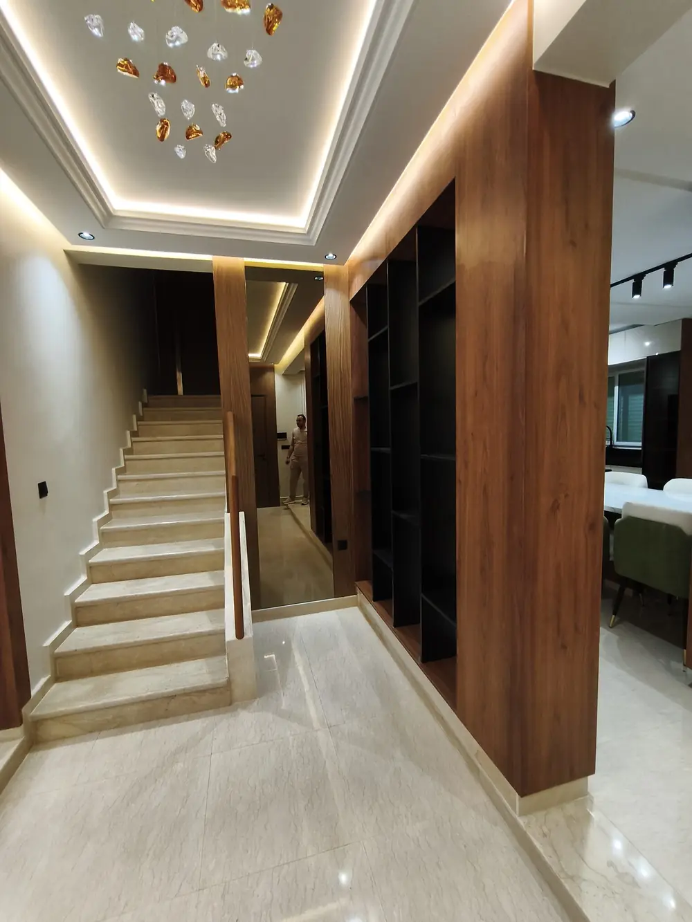 Hall d'une villa rénovée à Rabat : faux plafond lumineux et habillage bois
