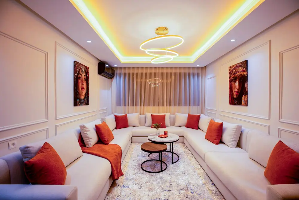 Le même salon livré : canapé en U, coussins orange et tableaux, appartement à Casablanca
