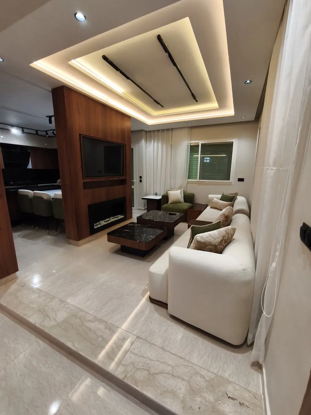 Salon ouvert, faux plafond lumineux et habillage bois (photo réelle)