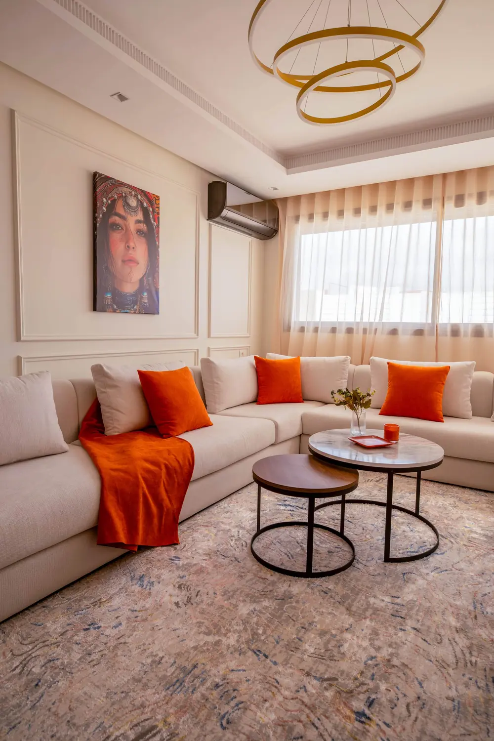Séjour de l'appartement Californie livré à Casablanca : canapé en U, coussins orange, suspension dorée
